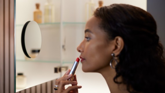 Woman applying make-up in the bathroom mirror Woman applying make-up in the bathroom mirror