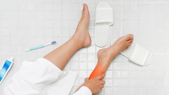 Woman holding her foot after slipping on bathroom floor Woman holding her foot after slipping on bathroom floor